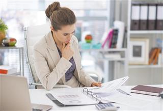 Thoughtful business woman documents in office