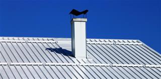 White aluminum roof with chimney and blue sky