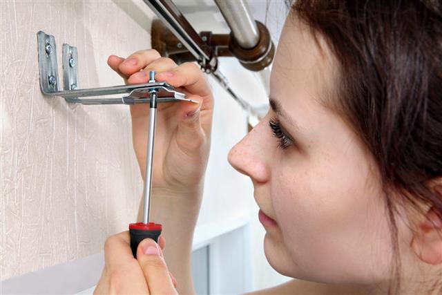 Girl fastens screwdriver bracket vertical blinds to wall