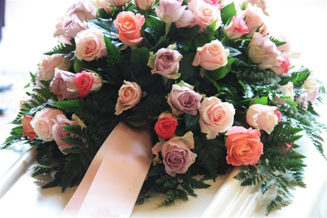 Pink sympathy flowers on a white coffin