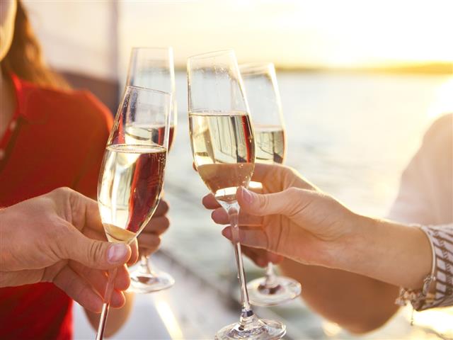 Happy friends with glasses of champagne on yacht. Vacation