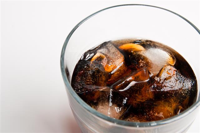 glass full of cola flavored soda and ice
