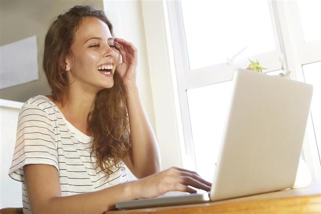 Young woman laughing with laptop at home