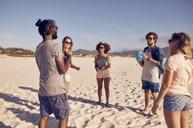 Group of friends on the beach playing with ball