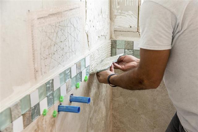 Tile border being installed on shower wall in home