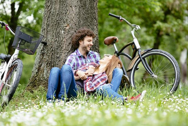 Young couple enjoy break after riding bicycle outdoors