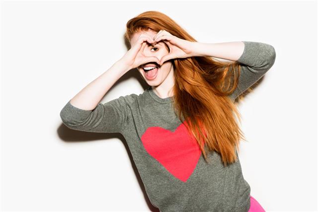 Girl wearing cardigan with heart making heart with hands