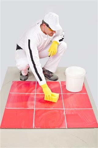 Worker with yellow gloves and sponge clean tiles
