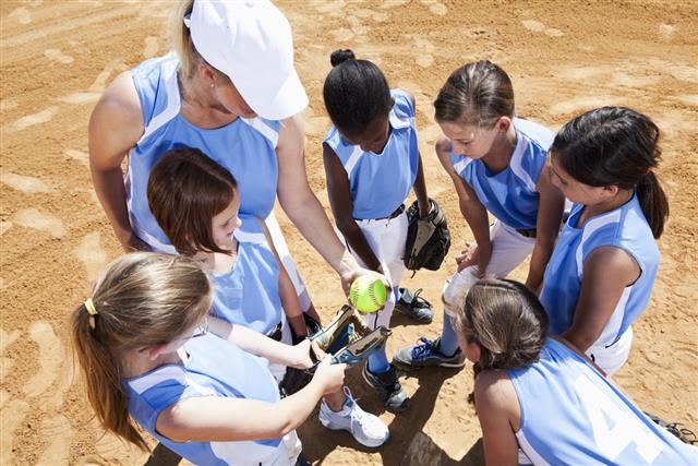 Softball team with coach in huddle