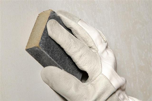 Hand sanding the wall with a sanding sponge