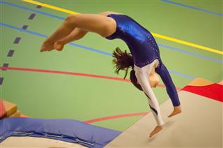 Young gymnast girl performing jump back handspring