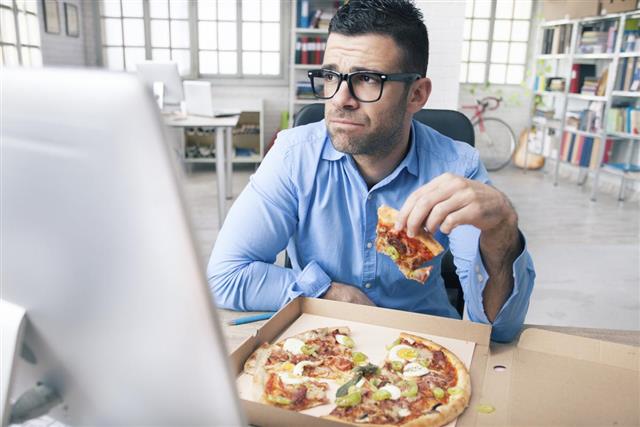 Tired businessman eating pizza at the office