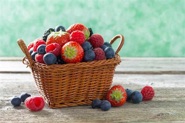 Basket with fresh juicy berries on a wooden table