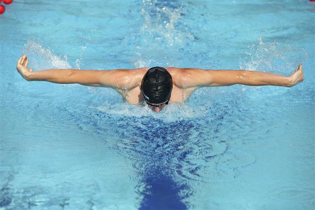 fit swimmer in cap breathing performing the butterfly stroke
