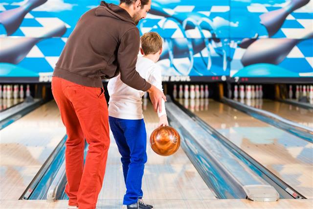 Father and son playing in bowling center