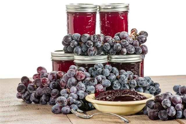 Bowl of grape jelly with jars isolated