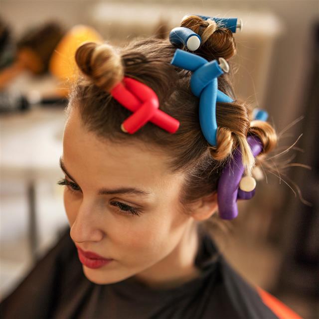 Pensive woman with curlers in hair