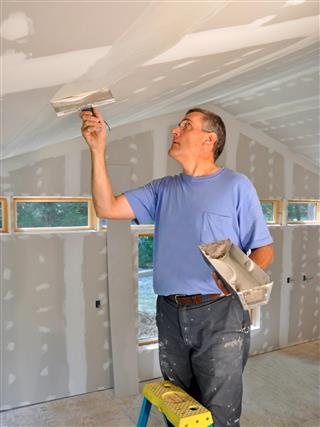 Man applying joint compound to finish drywall