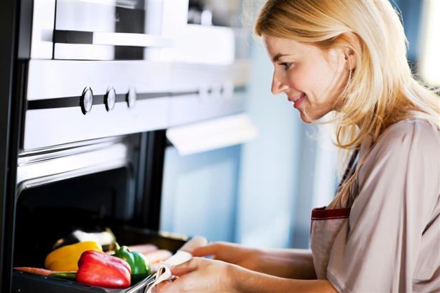 woman putting vegetables in oven