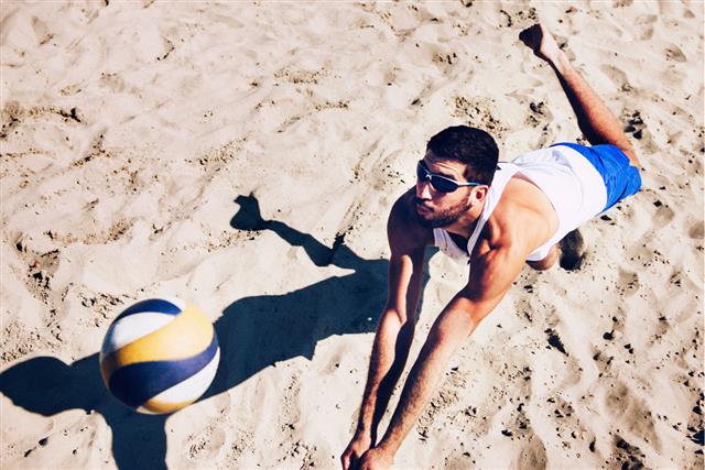 Beach volleyball player jumping for ball