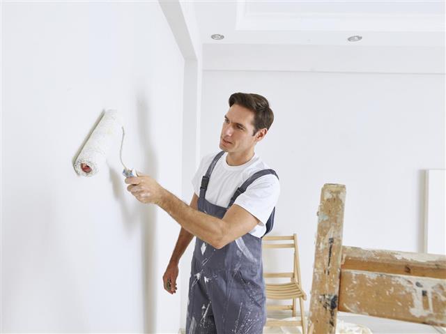 Man painting wall with a roller