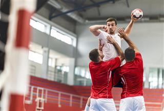 Handball player jumping and shooting at goal