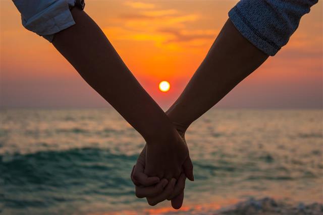 Hands holding on sunset at the sea???