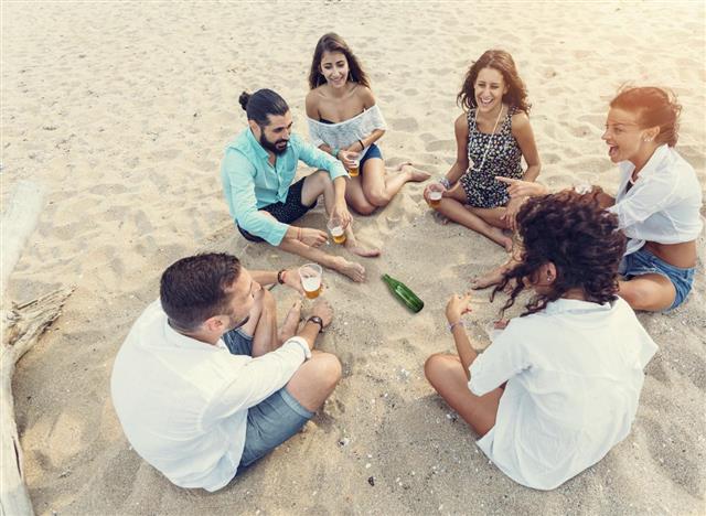 Group of friends playing spin the bottle at the beach