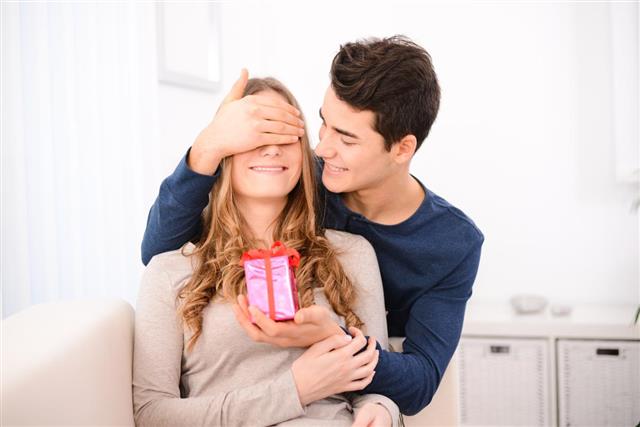 Young couple offering each other gifts for valentine lovers day