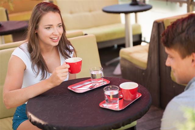 Young man and woman drinking coffee outdoor and chatting
