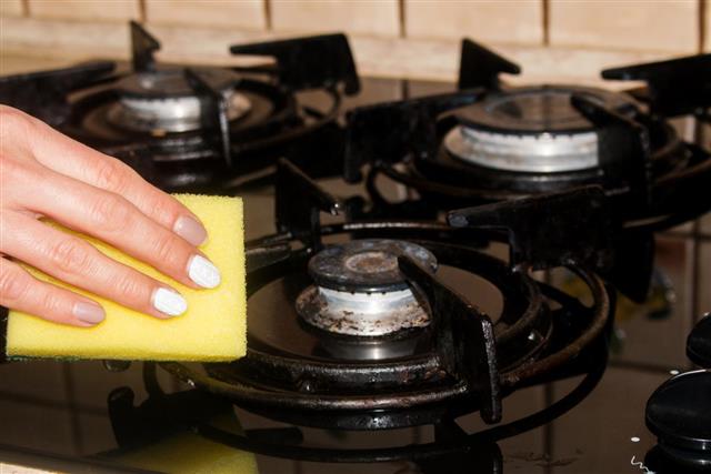 Woman hand cleaning stove in kitchen