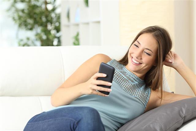 housewife using mobile phone on couch