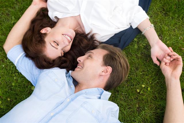 Couple looking at each other while lying on the grass