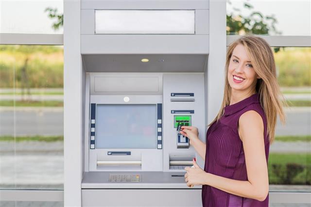 Young woman withdrawing cash at the ATM
