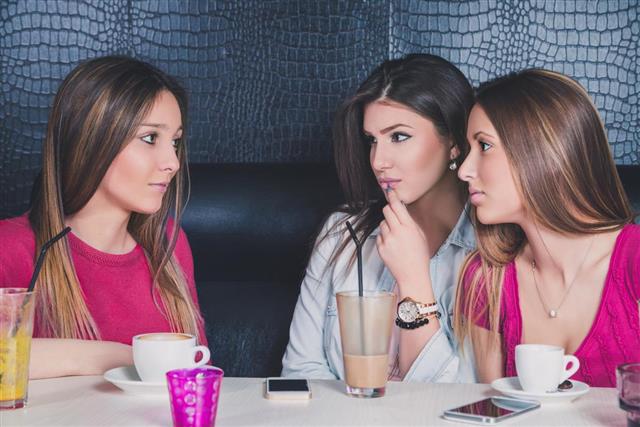 Three young girls having serious conversation in a cafe
