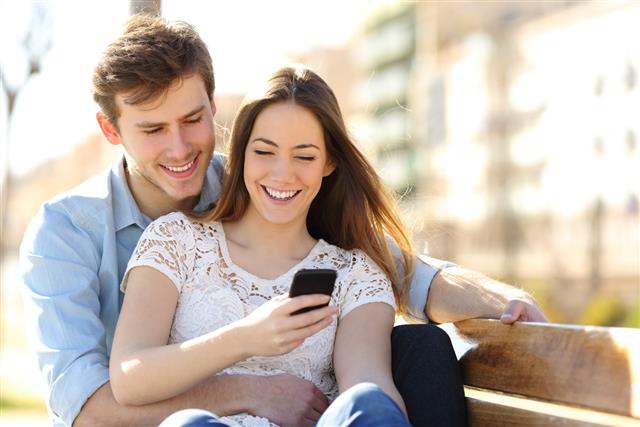 Couple sharing media in a smart phone in a park
