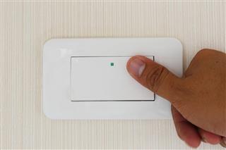 Man hand with finger on light switch