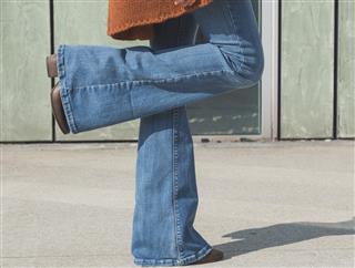 woman in blue jeans standing on one foot on cement floor