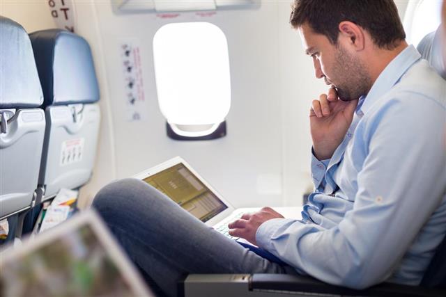 Businessman working with laptop on airplane