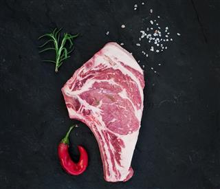 Raw fresh meat ribeye steak with salt, chili pepper