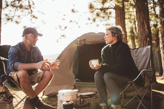 Mature man and woman sitting and talking at a campsite