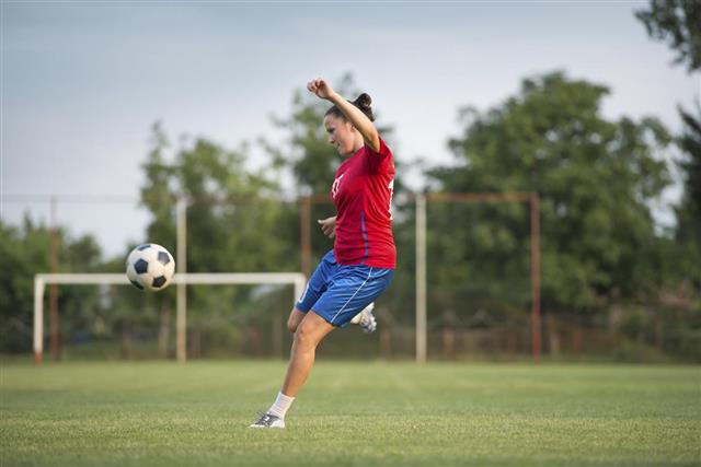 A female soccer player about to kick a ball