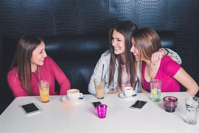 Three young girls having fun in a cafe