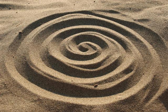 Hand drawing of a spiral in sand