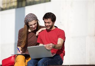 Two university students studying with laptop outdoors