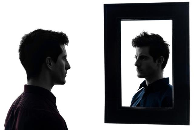 Man staring at his own reflection in mirror
