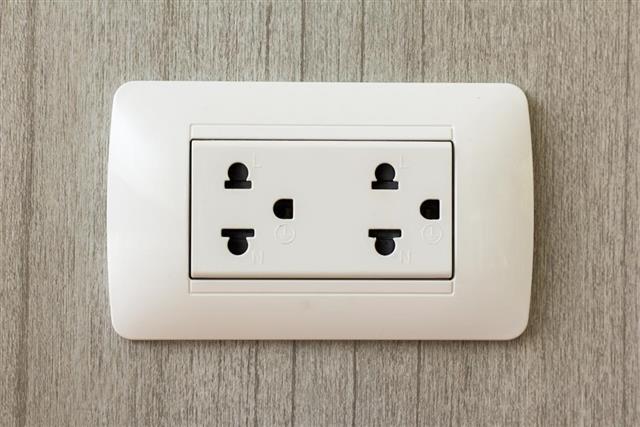 Electrical outlet on wood wallpaper