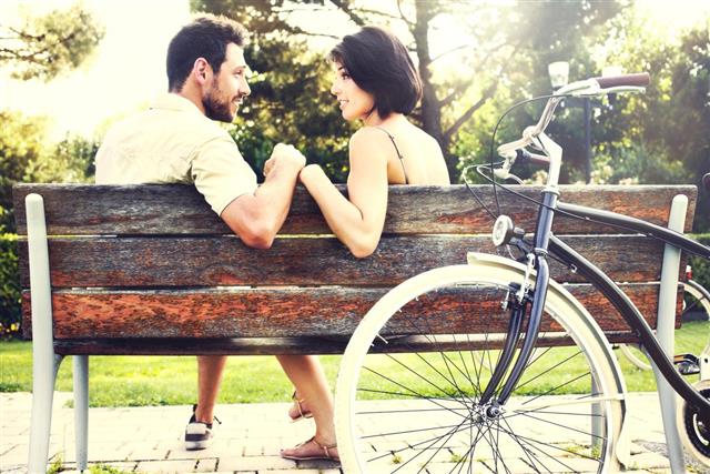 Couple in love sitting together on a bench with bikes