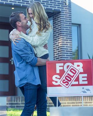 Couple standing in front of a new home.