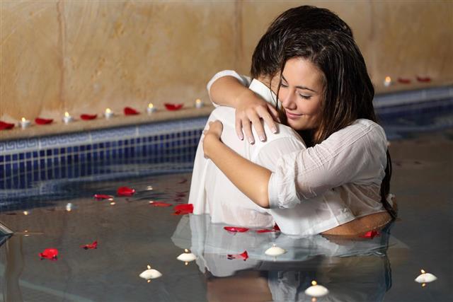 Romantic couple hugging in a pool with candle